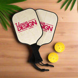 Two pickleball paddles with 'Your Design Here' text and three yellow pickleballs on a white background.