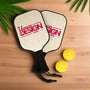 Two pickleball paddles with 'Your Design Here' text and three yellow pickleballs on a white background.