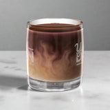 Glass_with_a_layered_drink_likely_coffee_and_cream_on_a_white_background
